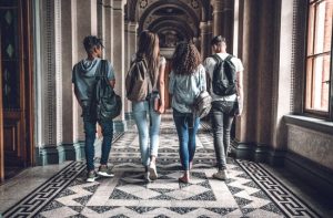 Four young adults walking down a school hall way