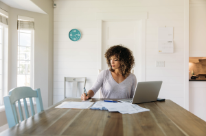 black woman sitting at a table with a computer and paperwork