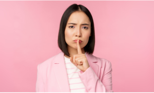 Asian women making a shhh sign wearing a pink blazer